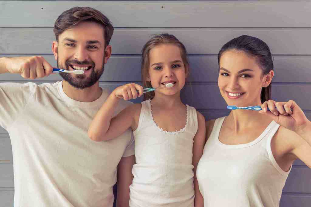 family of three brushing teeth
